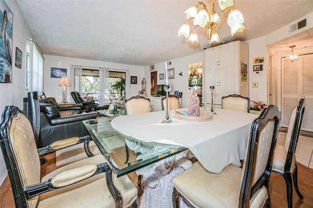 dining area featuring an inviting chandelier, wood-type flooring, and a textured ceiling