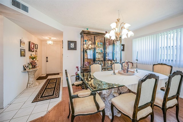 dining room featuring a textured ceiling, a notable chandelier, and light tile floors