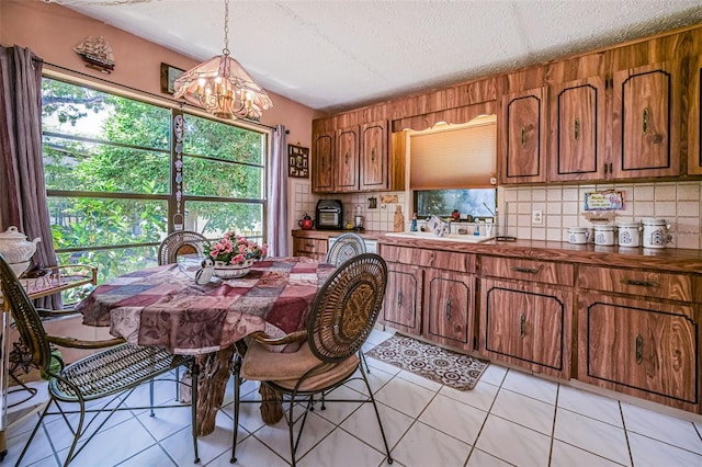 tiled dining area with sink, a textured ceiling, and a notable chandelier