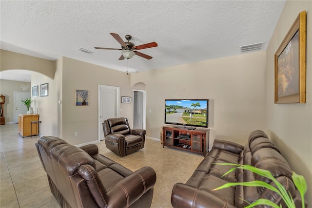 living room featuring ceiling fan, light tile flooring, and a textured ceiling