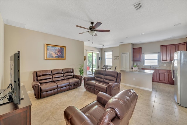 tiled living room featuring a textured ceiling, ceiling fan, and sink