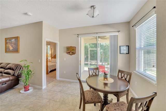 dining space with ceiling fan, light tile floors, a wealth of natural light, and a textured ceiling