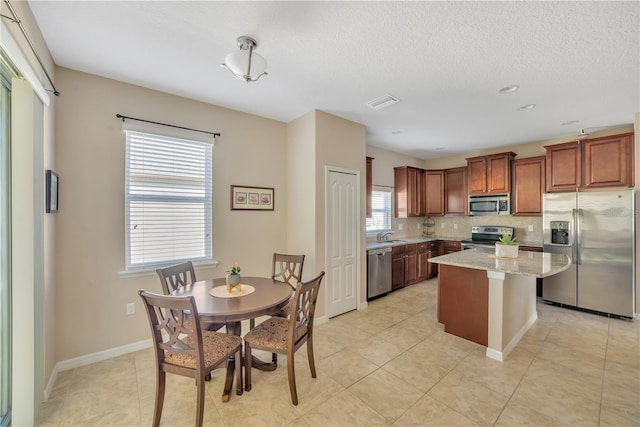 kitchen with backsplash, a kitchen island, stainless steel appliances, and light tile floors