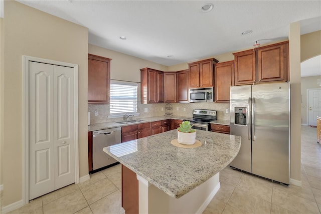 kitchen featuring a kitchen island, stainless steel appliances, light tile flooring, tasteful backsplash, and light stone counters