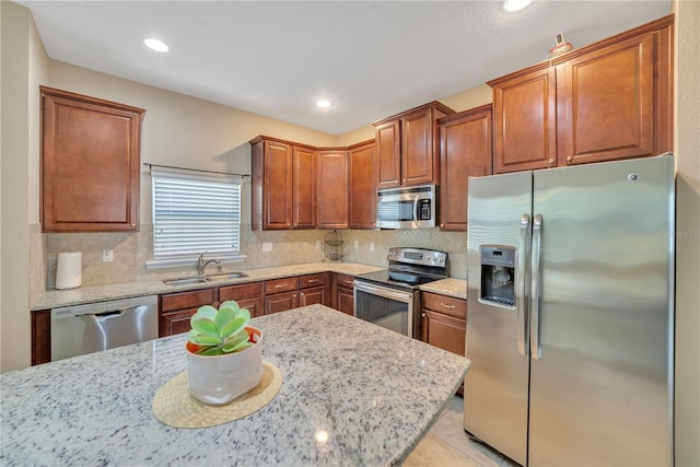 kitchen with backsplash, stainless steel appliances, sink, and light stone countertops