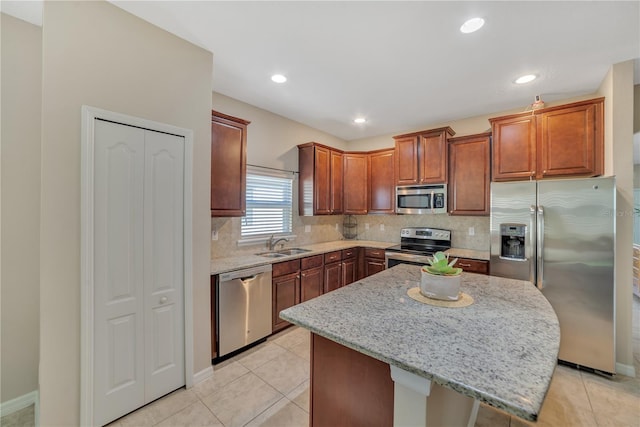 kitchen with a kitchen island, backsplash, light tile flooring, stainless steel appliances, and light stone countertops