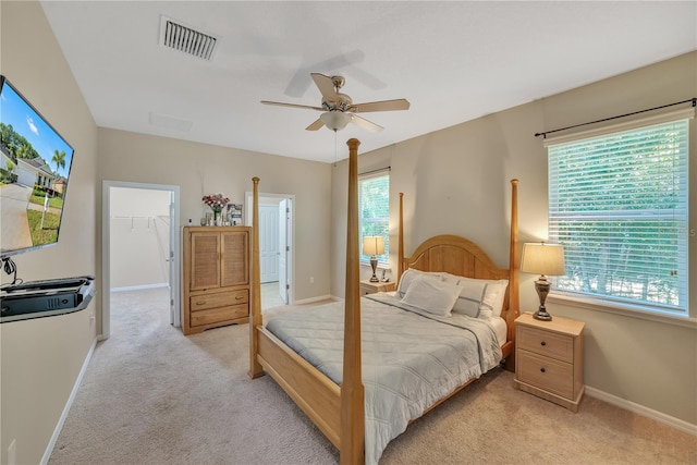 bedroom featuring light colored carpet, a spacious closet, ceiling fan, and a closet