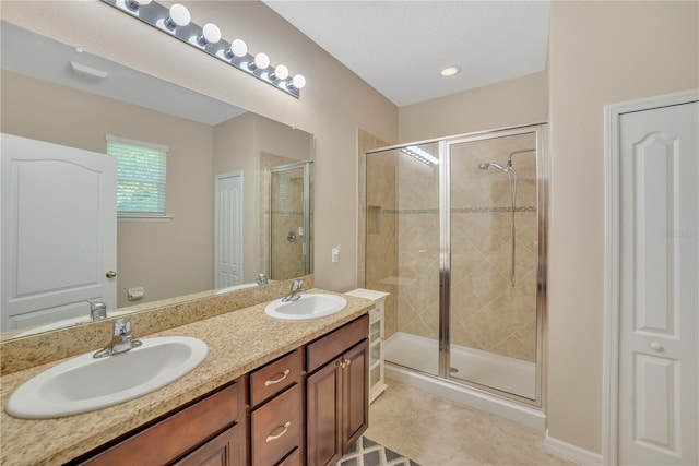 bathroom with a shower with door, tile floors, vanity with extensive cabinet space, and double sink