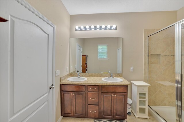 bathroom featuring a shower with door, large vanity, tile floors, and dual sinks