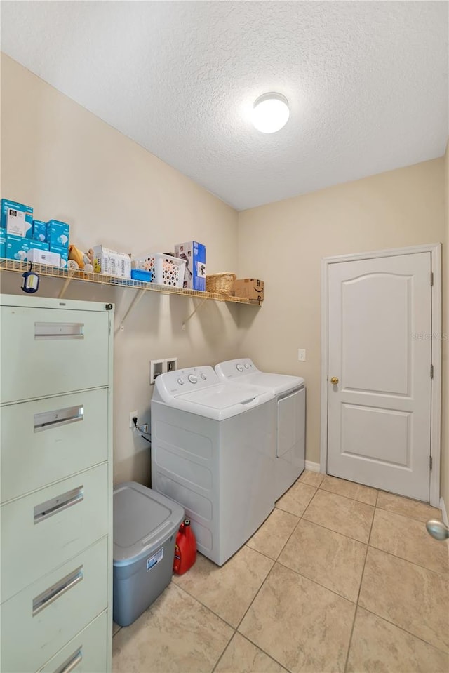 laundry area featuring hookup for a washing machine, washing machine and dryer, light tile floors, and a textured ceiling