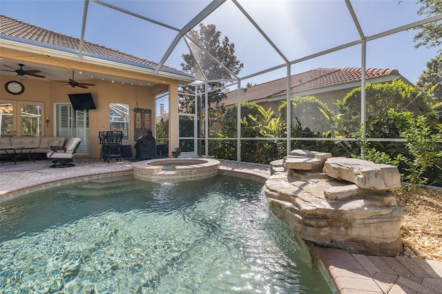 view of swimming pool with an in ground hot tub, glass enclosure, ceiling fan, and a patio area