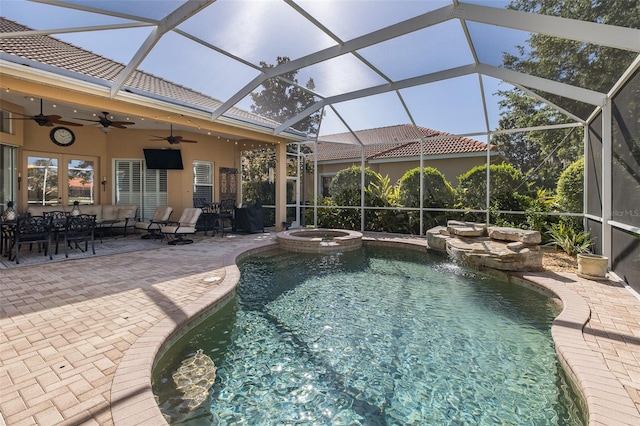 view of swimming pool featuring a patio area, an in ground hot tub, ceiling fan, and glass enclosure