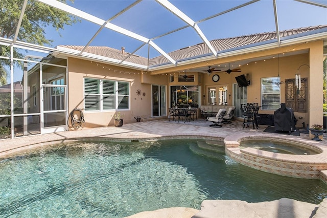 view of pool with an in ground hot tub, glass enclosure, ceiling fan, and a patio area