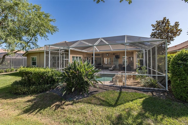 rear view of house featuring glass enclosure, a patio area, and a yard