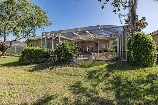 rear view of house featuring a lawn and glass enclosure