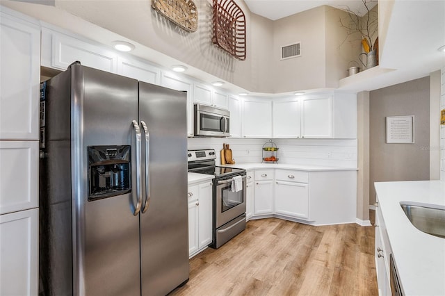 kitchen featuring light countertops, visible vents, light wood-style flooring, appliances with stainless steel finishes, and white cabinets