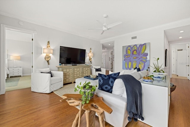 living room featuring ceiling fan, light wood-type flooring, and ornamental molding