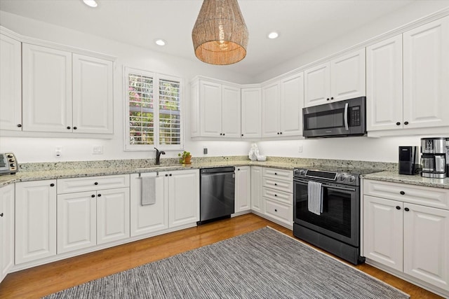 kitchen with white cabinetry, stainless steel appliances, decorative light fixtures, and light wood-type flooring