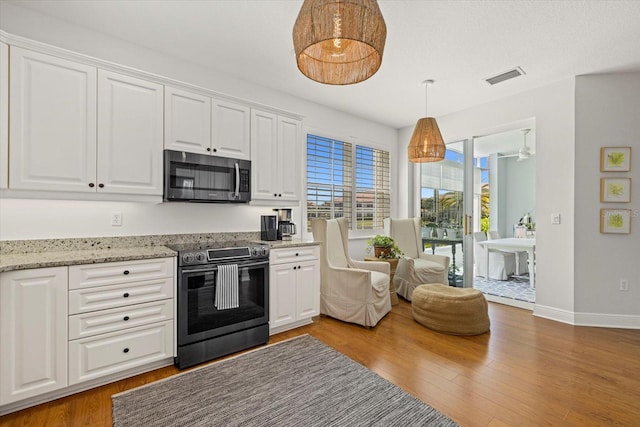 kitchen featuring white cabinets, stainless steel appliances, hardwood / wood-style flooring, and hanging light fixtures