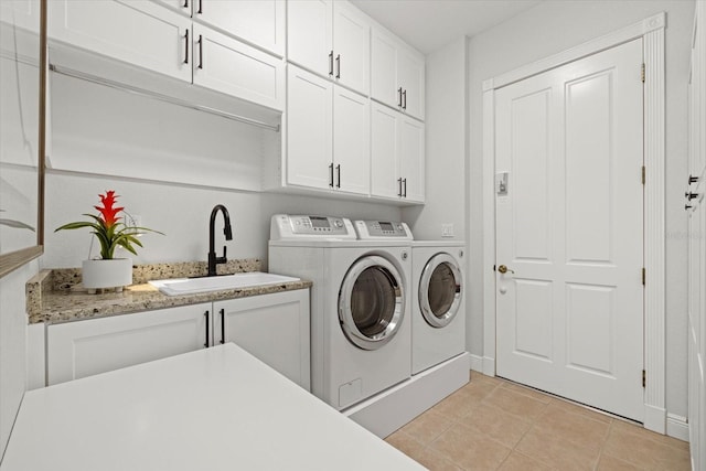 laundry area with washer and clothes dryer, cabinets, light tile patterned floors, and sink