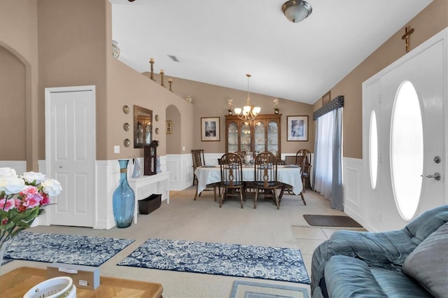 living room featuring lofted ceiling, a notable chandelier, and carpet flooring