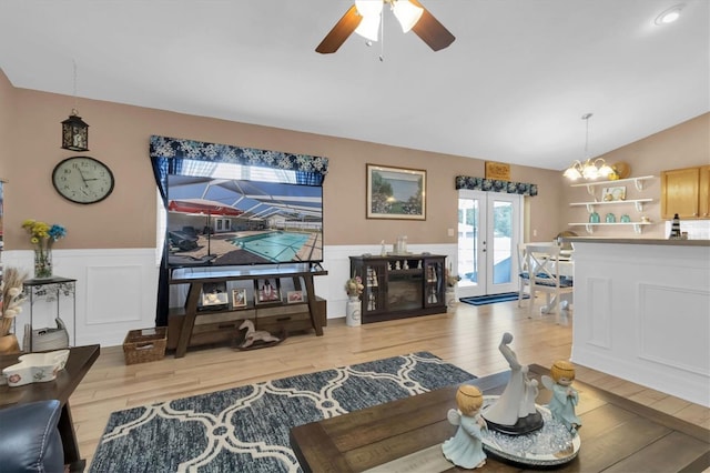 living room featuring ceiling fan with notable chandelier, vaulted ceiling, and light wood-type flooring