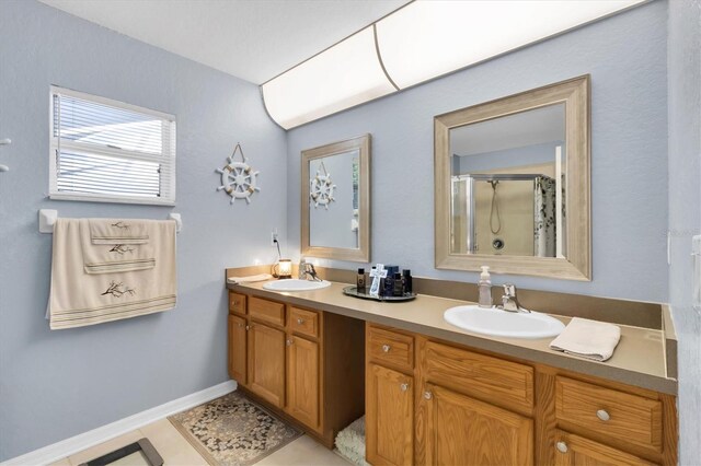 bathroom with tile flooring, dual sinks, a shower with door, and large vanity