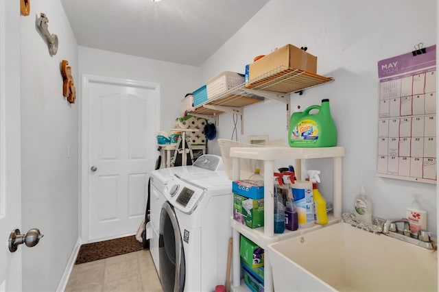 clothes washing area featuring sink, light tile floors, and washer and clothes dryer