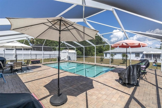 view of swimming pool featuring a patio, a lanai, and a storage shed