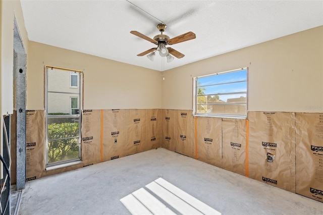 carpeted spare room with wooden walls and ceiling fan