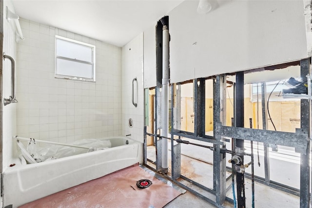 bathroom with concrete flooring and a bathtub