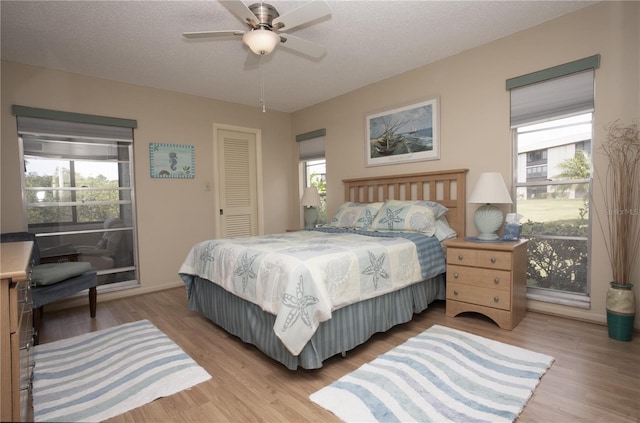 bedroom with a closet, light hardwood / wood-style floors, multiple windows, and a textured ceiling