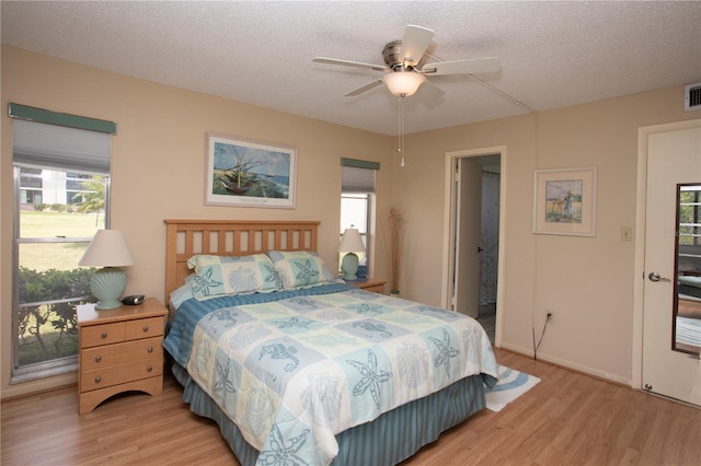 bedroom featuring ceiling fan, light hardwood / wood-style flooring, and a textured ceiling