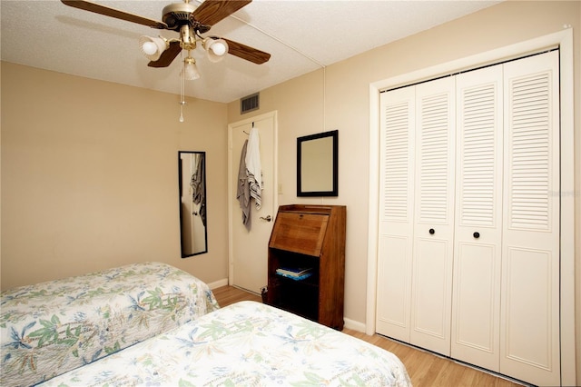 bedroom featuring a textured ceiling, a closet, ceiling fan, and light wood-type flooring