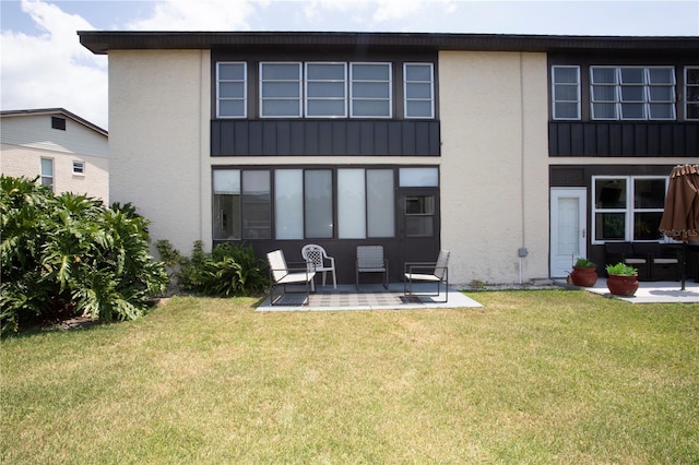 back of property with a lawn and a patio area