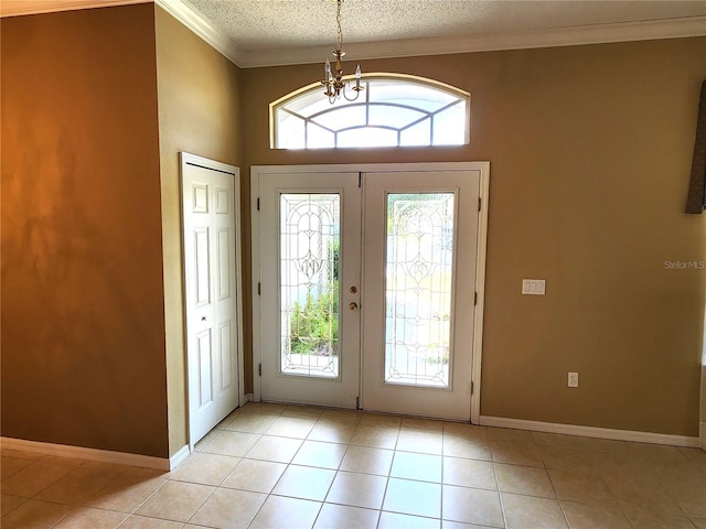 tiled foyer entrance featuring a healthy amount of sunlight, a textured ceiling, french doors, and crown molding