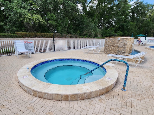 view of swimming pool featuring a hot tub and a patio area