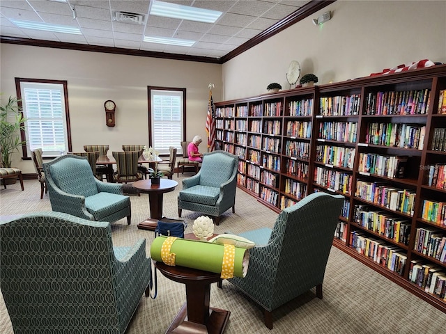 living area with a wealth of natural light, carpet flooring, and ornamental molding