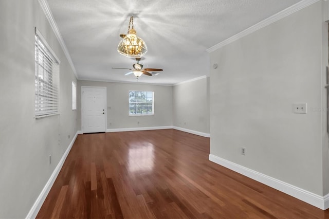 spare room with ornamental molding, dark wood-type flooring, a textured ceiling, and ceiling fan with notable chandelier