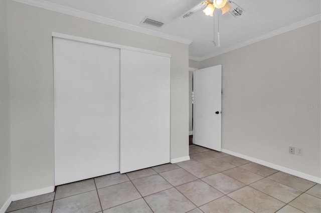 unfurnished bedroom featuring ceiling fan, ornamental molding, a closet, and light tile flooring