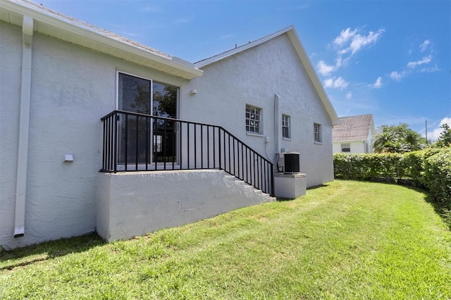 view of side of home featuring a lawn and central AC unit