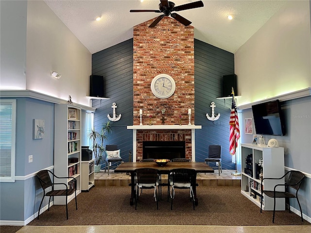 carpeted dining room with brick wall, a fireplace, ceiling fan, high vaulted ceiling, and a textured ceiling