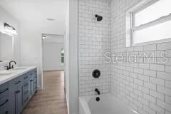 bathroom with vanity with extensive cabinet space, tiled shower / bath, and hardwood / wood-style floors