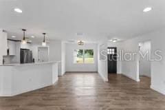 kitchen with pendant lighting, dark wood-type flooring, and fridge