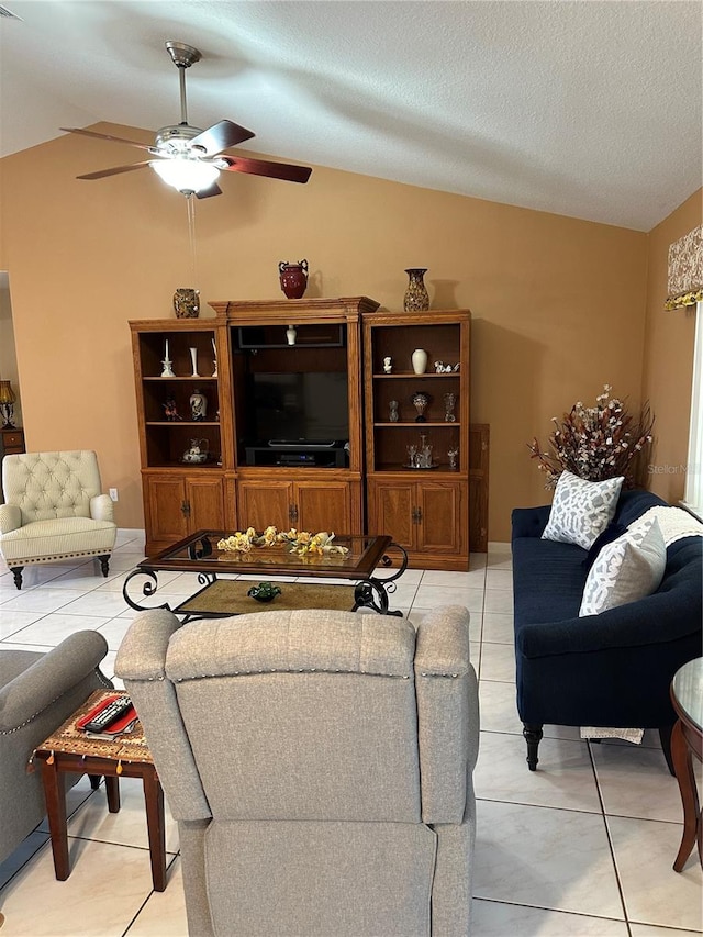 living room with ceiling fan, lofted ceiling, a textured ceiling, and light tile patterned floors