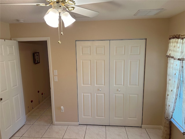 unfurnished bedroom with ceiling fan, light tile patterned floors, and a closet