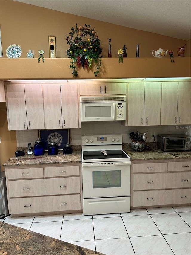 kitchen with light brown cabinets, white appliances, and lofted ceiling