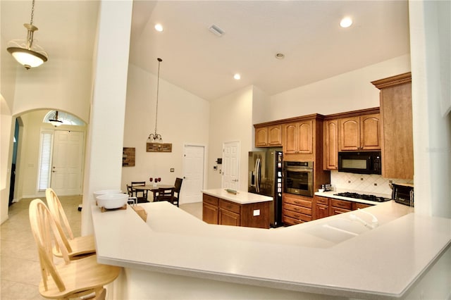 kitchen featuring black appliances, tasteful backsplash, pendant lighting, and a kitchen island