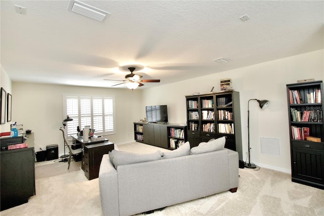 carpeted living room with a textured ceiling and ceiling fan