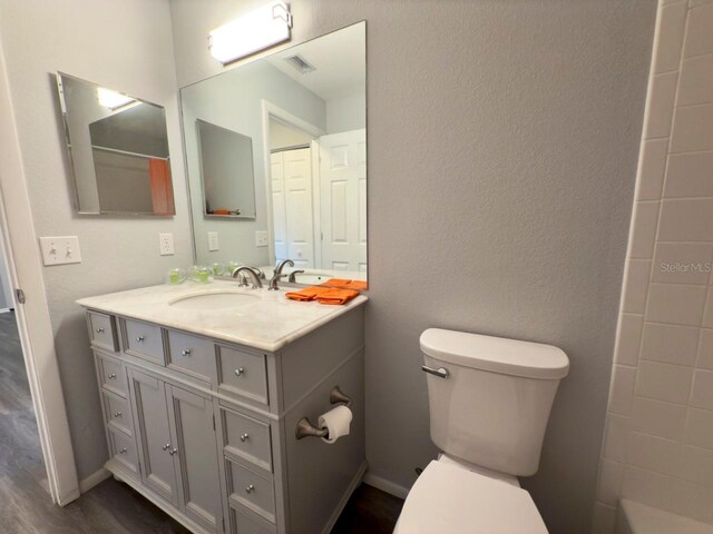 bathroom featuring vanity, walk in shower, and toilet